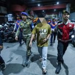 Petugas mengamankan juru parkir tidak resmi di Tanjung Anom, kawasan Jalan Tunjungan Surabaya, Jumat (11/7/2025) malam.