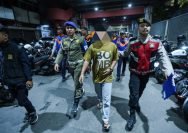 Petugas mengamankan juru parkir tidak resmi di Tanjung Anom, kawasan Jalan Tunjungan Surabaya, Jumat (11/7/2025) malam.