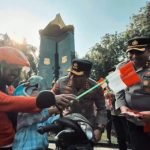 Pembagian bendera merah putih kepada pengendara berlangsung di Jalan Polisi Istimewa, Surabaya, Rabu (13/8/2025). (Polrestabes Surabaya)